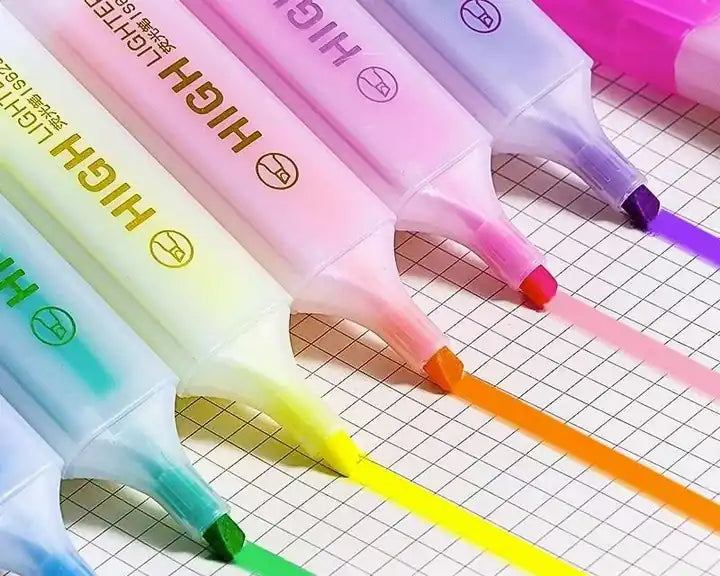 Close-up of six chisel tip highlighters drawing bright lines on grid paper